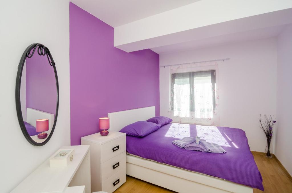 Dormitorio púrpura con cama y espejo en Apartment Atlant, en Dubrovnik