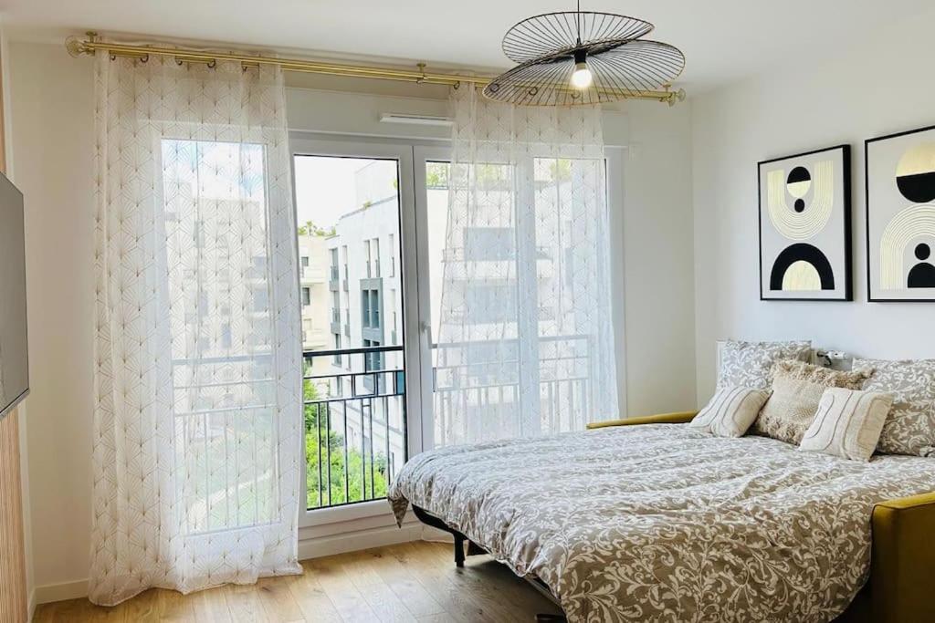 ein Schlafzimmer mit einem Bett und einem großen Fenster in der Unterkunft Bel appartement à 5 mn de Paris très proche Métro 13 et 14 in Saint-Ouen