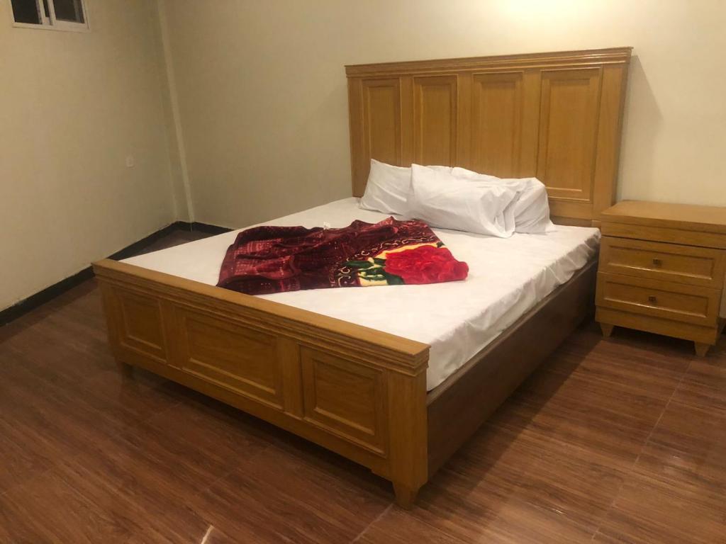 Un dormitorio con una cama grande con cabecero de madera. en Al Buraq Hotel, en Islamabad