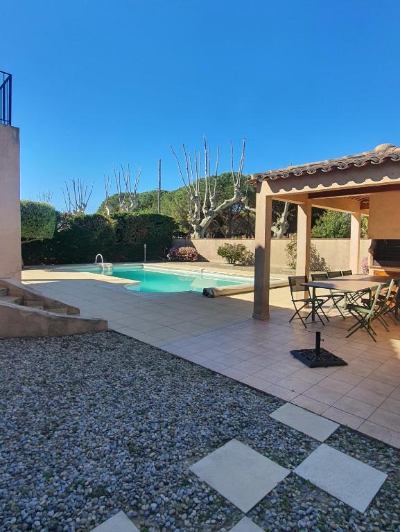 une terrasse avec une table de pique-nique et une piscine dans l'établissement Villa proche de la plage, à La Londe-les-Maures