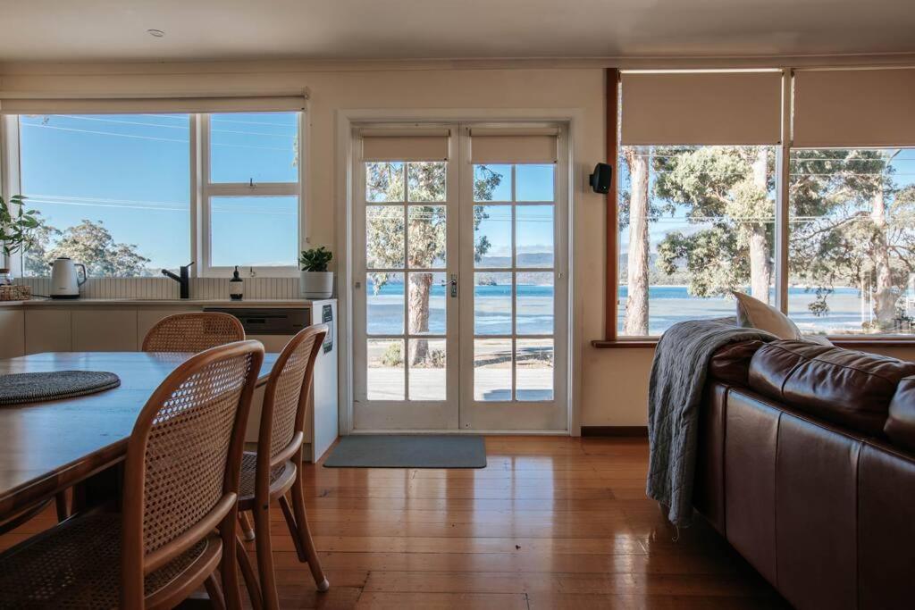 un soggiorno con tavolo, sedie e finestre di Little Possum Shack waterfront cottage a Port Arthur