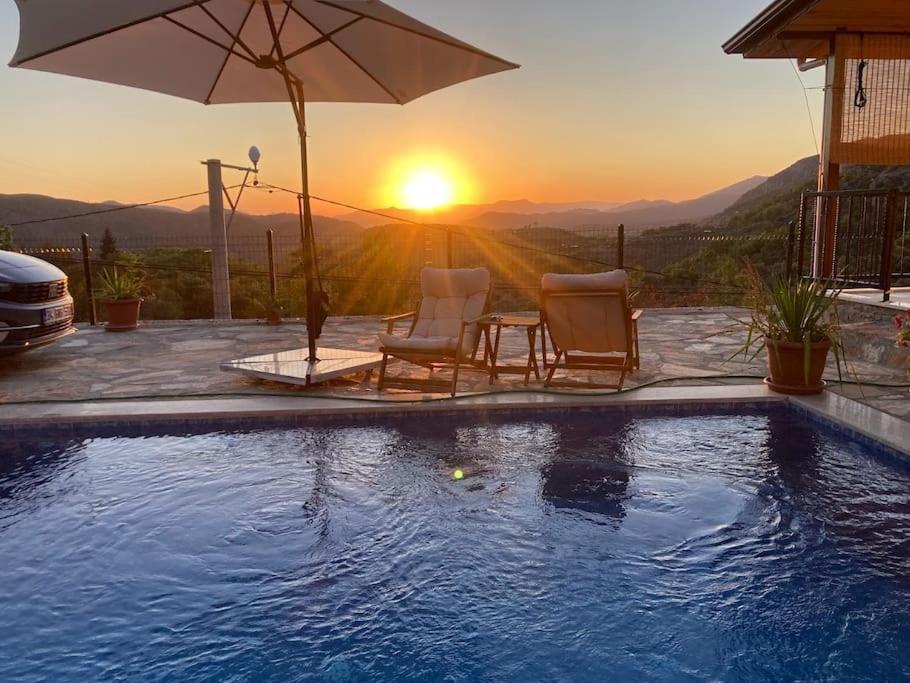 a pool with two chairs and an umbrella with the sunset at Magnificent sunset view in Fethiye