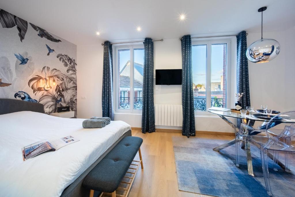 a bedroom with a bed and a desk and windows at Appart 2 personnes à 50m des commerces & mer in Barneville-Carteret