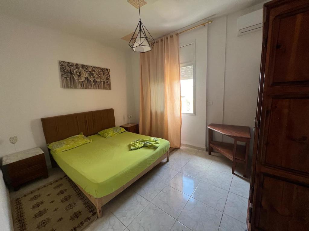 a bedroom with a green bed and a desk at Appartement au calme in Bir Kassa