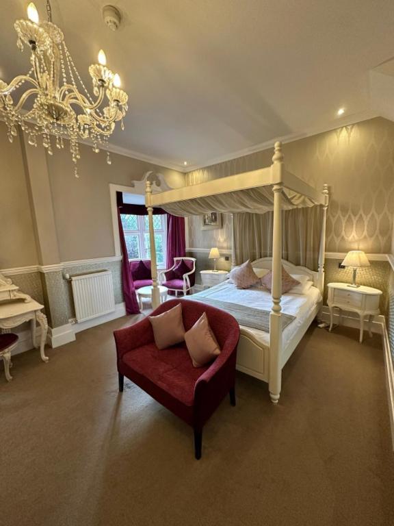 a bedroom with a canopy bed and a red couch at Langtry Manor Hotel in Bournemouth