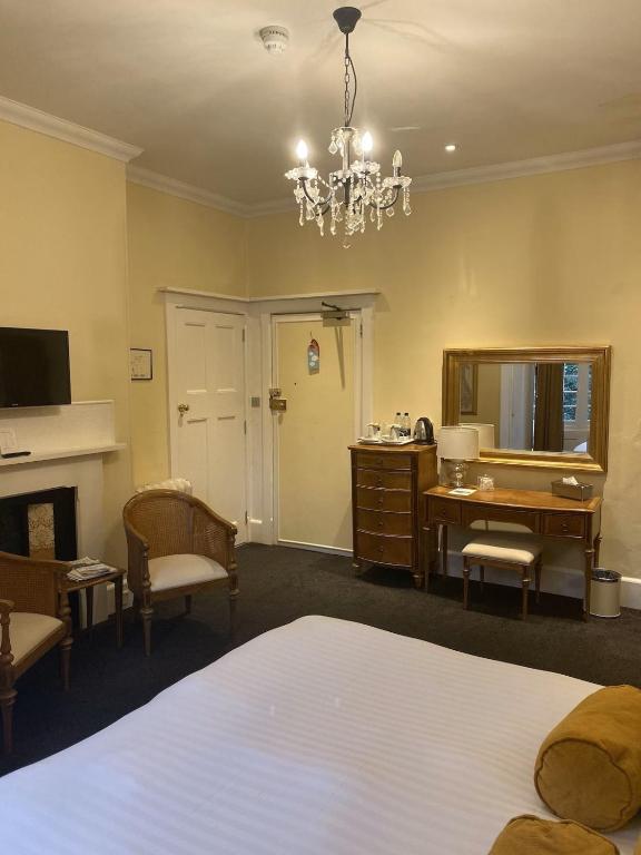 a bedroom with a bed and a desk and a mirror at Langtry Manor Hotel in Bournemouth