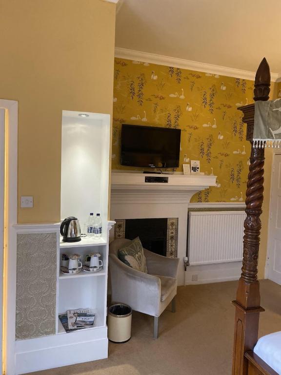 a living room with a fireplace with a tv above it at Langtry Manor Hotel in Bournemouth