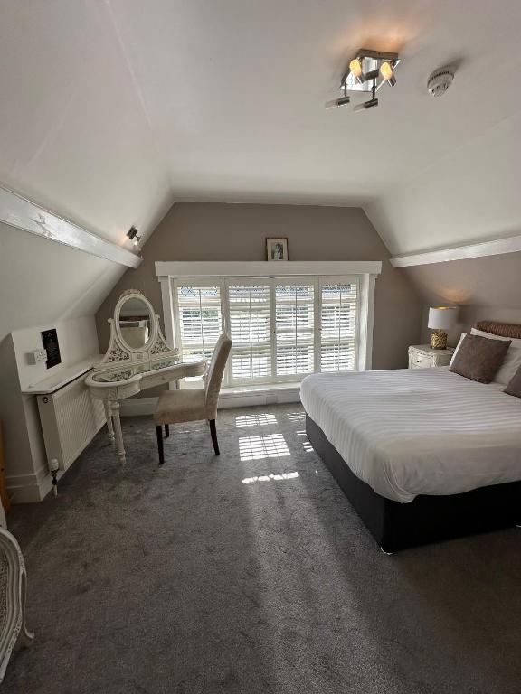 a bedroom with a bed and a desk and a window at Langtry Manor Hotel in Bournemouth