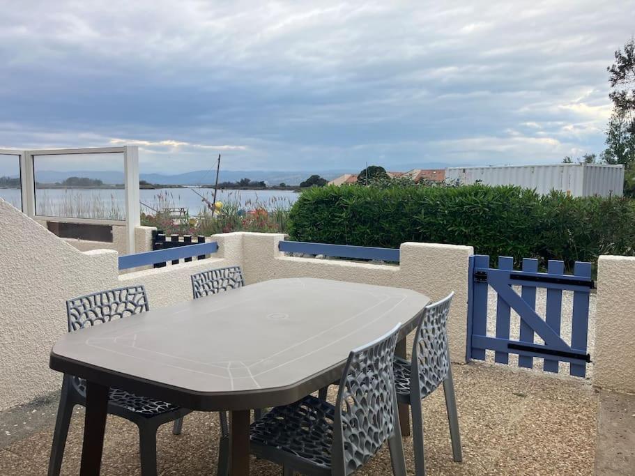une table et des chaises sur une terrasse avec une clôture dans l'établissement Appartement vue lac, à Leucate