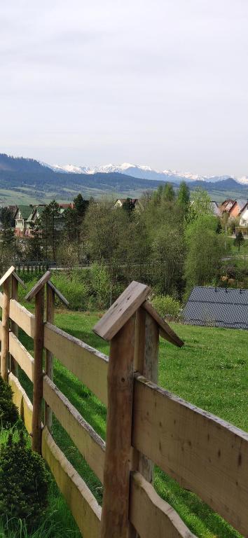 einen Holzzaun mit Blick auf ein Feld in der Unterkunft Góralskie Domki na Podhalu - z jacuzzi in Maniowy