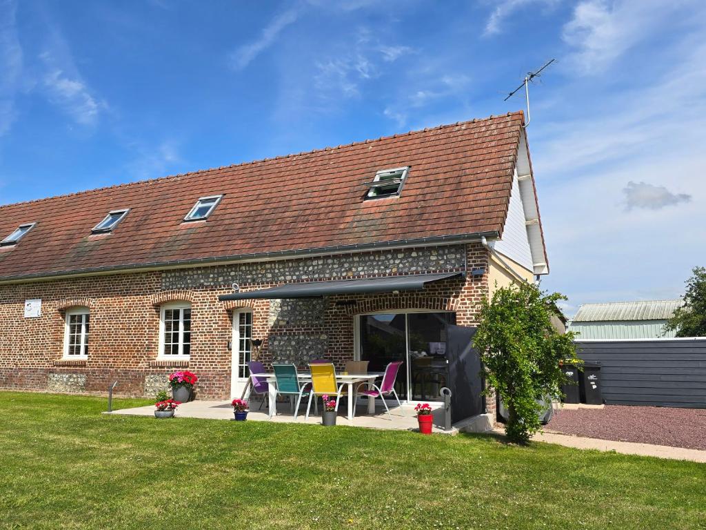 une maison en briques avec une table et des chaises à l'extérieur dans l'établissement Les 3 Hirondelles - Maison avec grand jardin, à Bracquemont