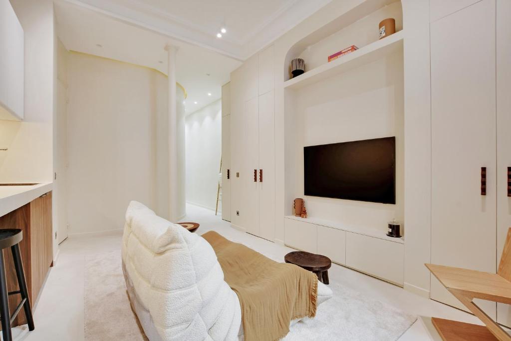 un salon blanc avec une télévision et un canapé dans l'établissement Le petit luxe parisien, à Paris