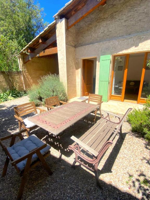 - une table de pique-nique et des chaises en face d'une maison dans l'établissement Maison provençale au milieu des champs, à Robion