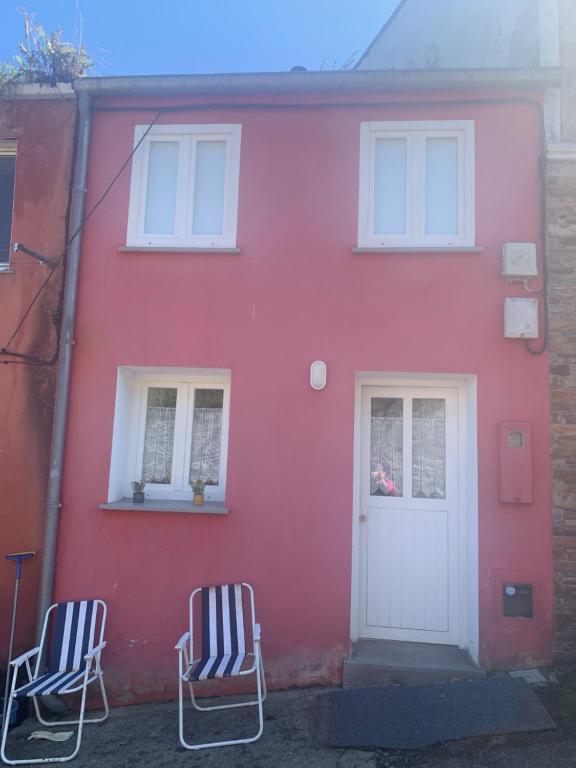 zwei Stühle vor einem roten Haus in der Unterkunft Casa Muralla in Ribadeo