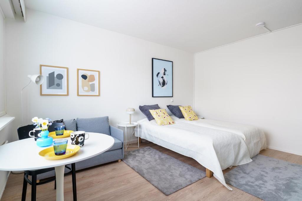 a white bedroom with a bed and a table at Northern Lights City Cabin in Rovaniemi