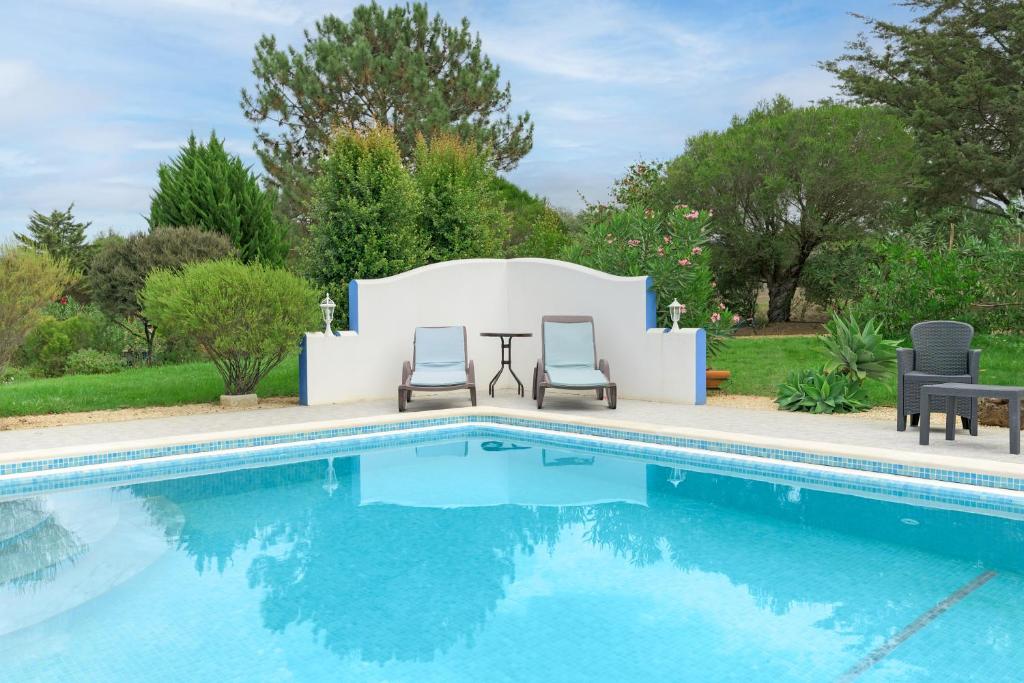 una piscina con due sedie e un tavolo accanto ad essa di Casa Alecrim - Selão da Eira a Pedreneiras