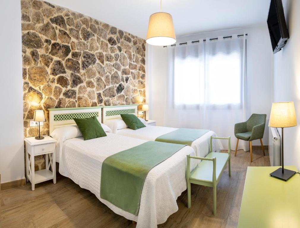 two beds in a room with a stone wall at Apartamentos rurales Posada de Monfragüe con jacuzzi in Malpartida de Plasencia