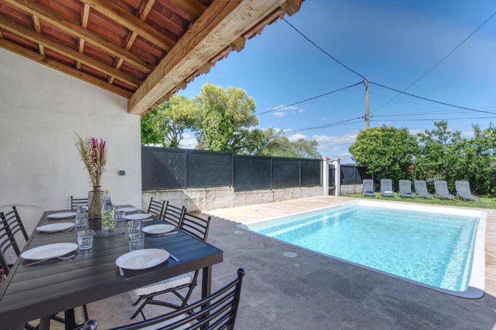un patio avec une table et une piscine dans l'établissement L'Oustal Occitan, à Saint-Privat-des-Vieux
