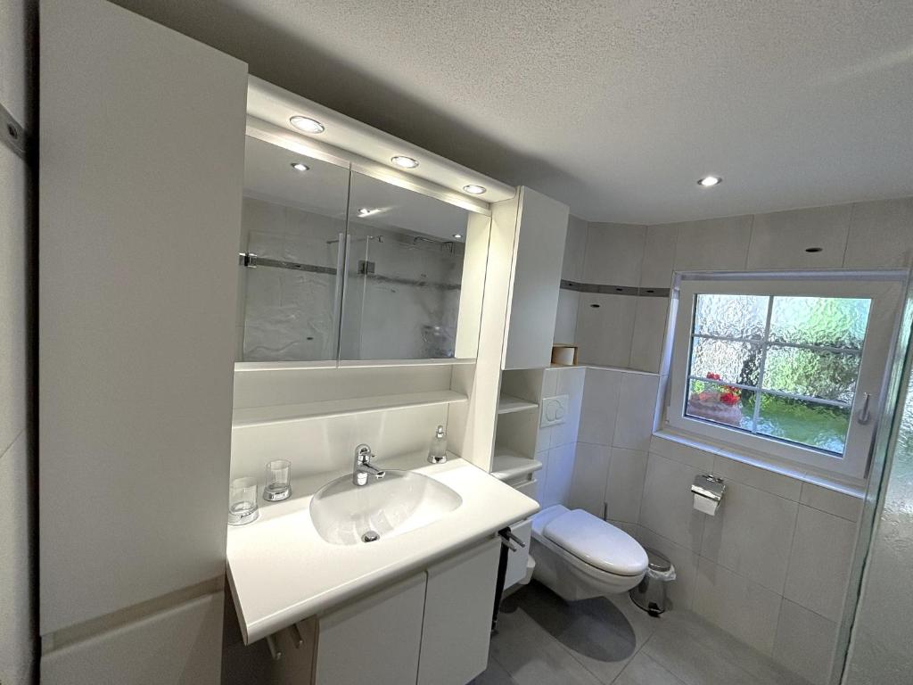 a white bathroom with a sink and a toilet at Chalet Medi in Zermatt