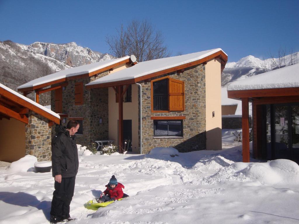 a man and a child in the snow in front of a house at Les Granges de Leo in Aston