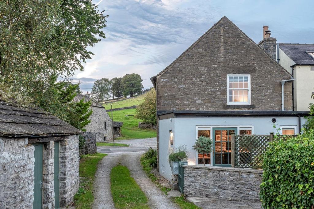 an old stone house with a stone path leading up to it at Sweet Pea Cottage in Tideswell