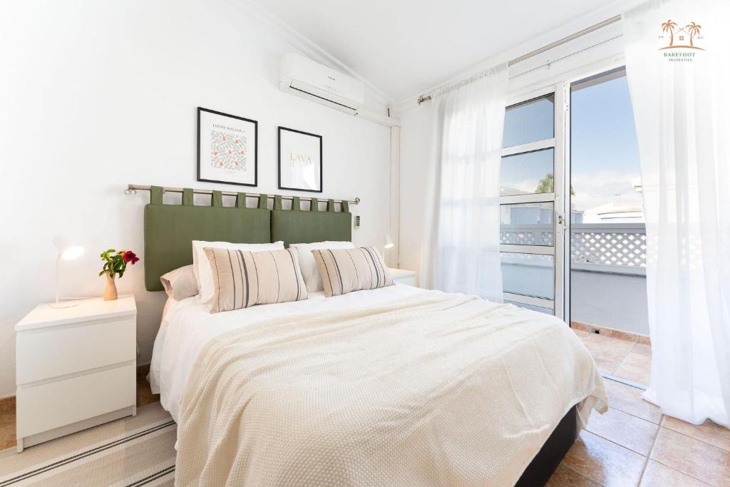 a white bedroom with a large bed and a window at Linda House in Maspalomas