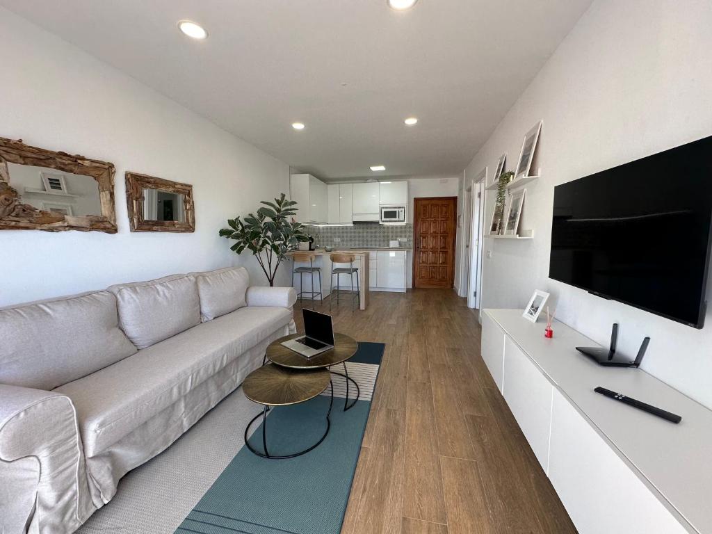 Una sala de estar con un sofá blanco y un televisor. en VV Las Caletillas, en Candelaria