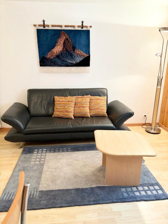 a black leather couch in a living room with a table at Chalet Medi in Zermatt