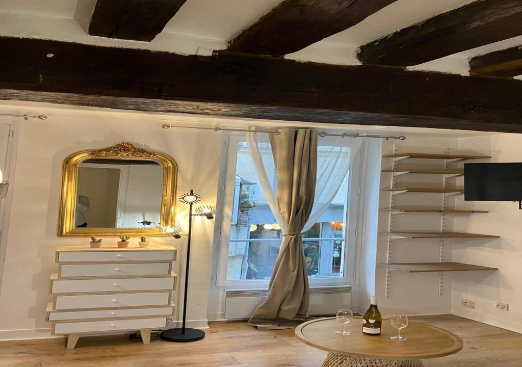Cette chambre comprend un miroir, une commode et une fenêtre. dans l'établissement Elegant Retreat by Le Marais, à Paris