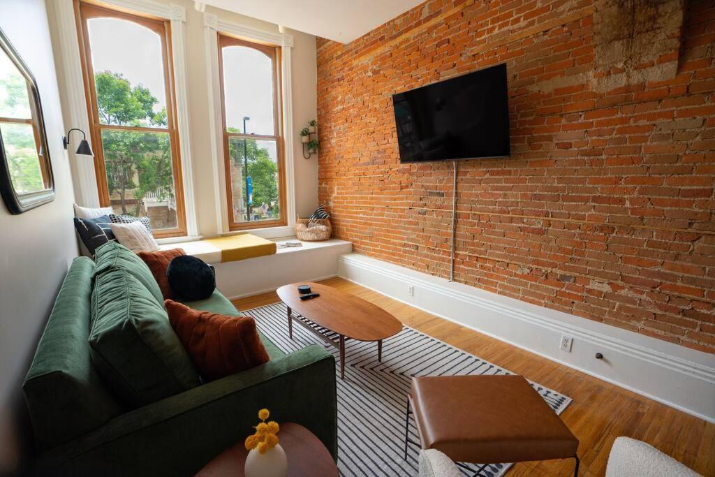 a living room with a couch and a brick wall at The Getaway in DT Northfield! in Northfield