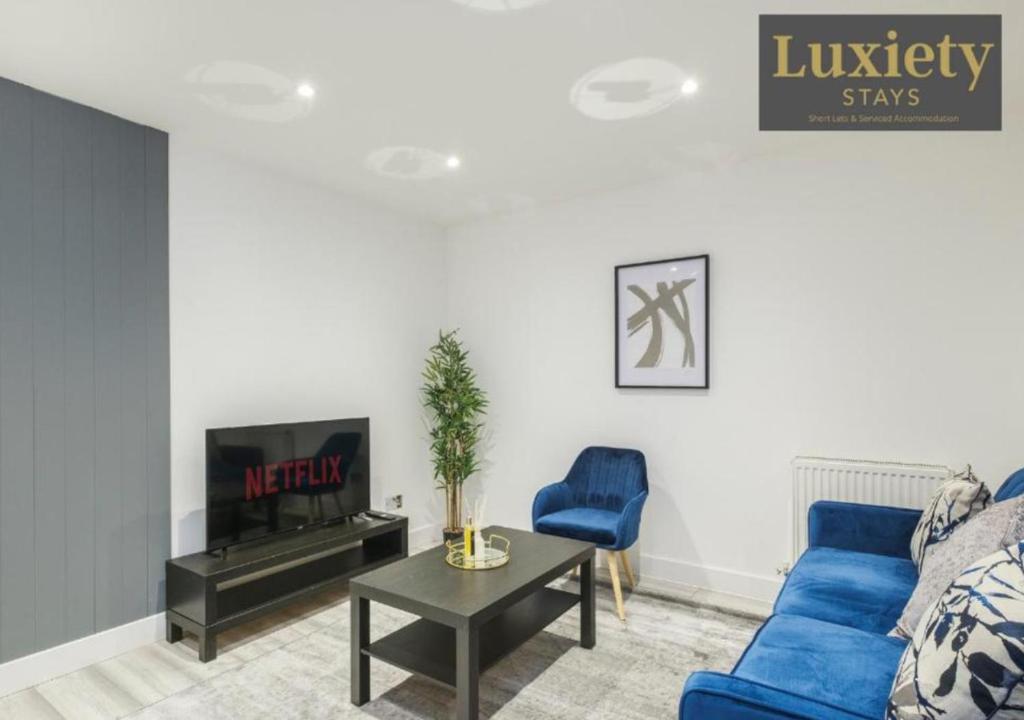 a living room with a blue couch and a tv at Modern & Elegant 1BR City Centre - Near High St & Southend Beach by Luxiety Stays in Southend-on-Sea