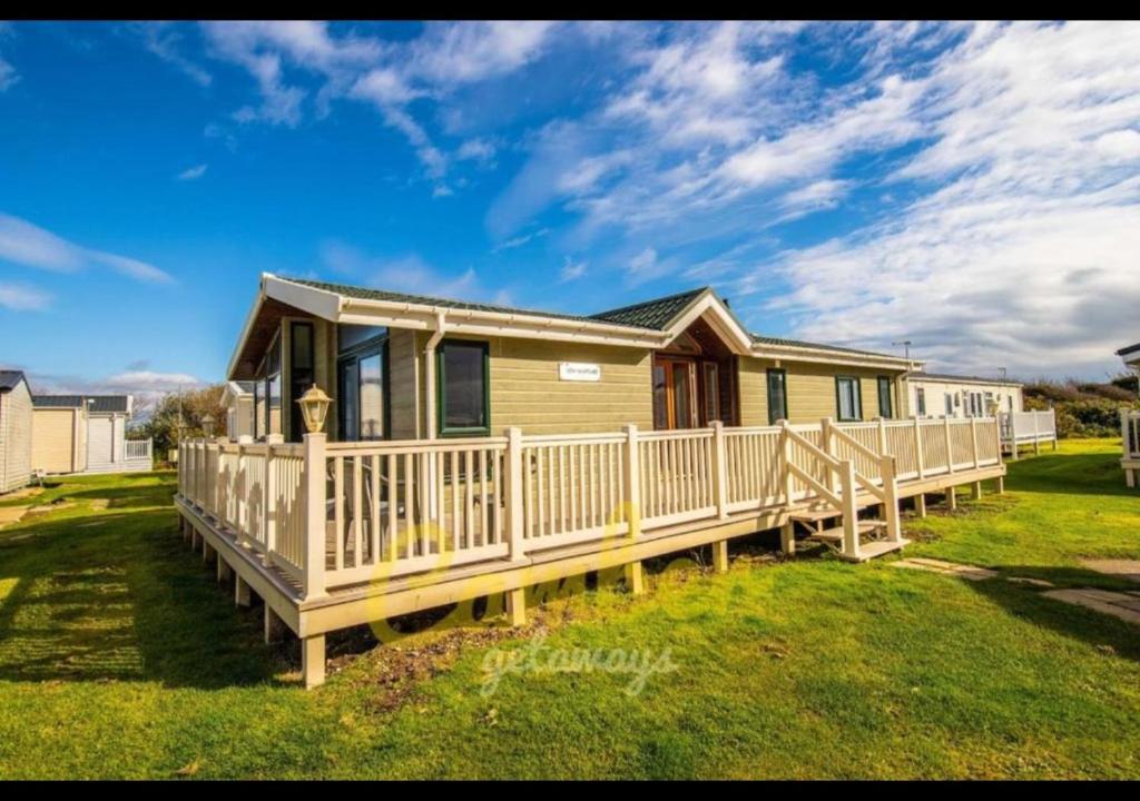 a manufactured home with a porch and a house at MP768 - Camber Sands Holiday Park - Huge Lodge - Small dog friendly - sleeps 8 in Camber