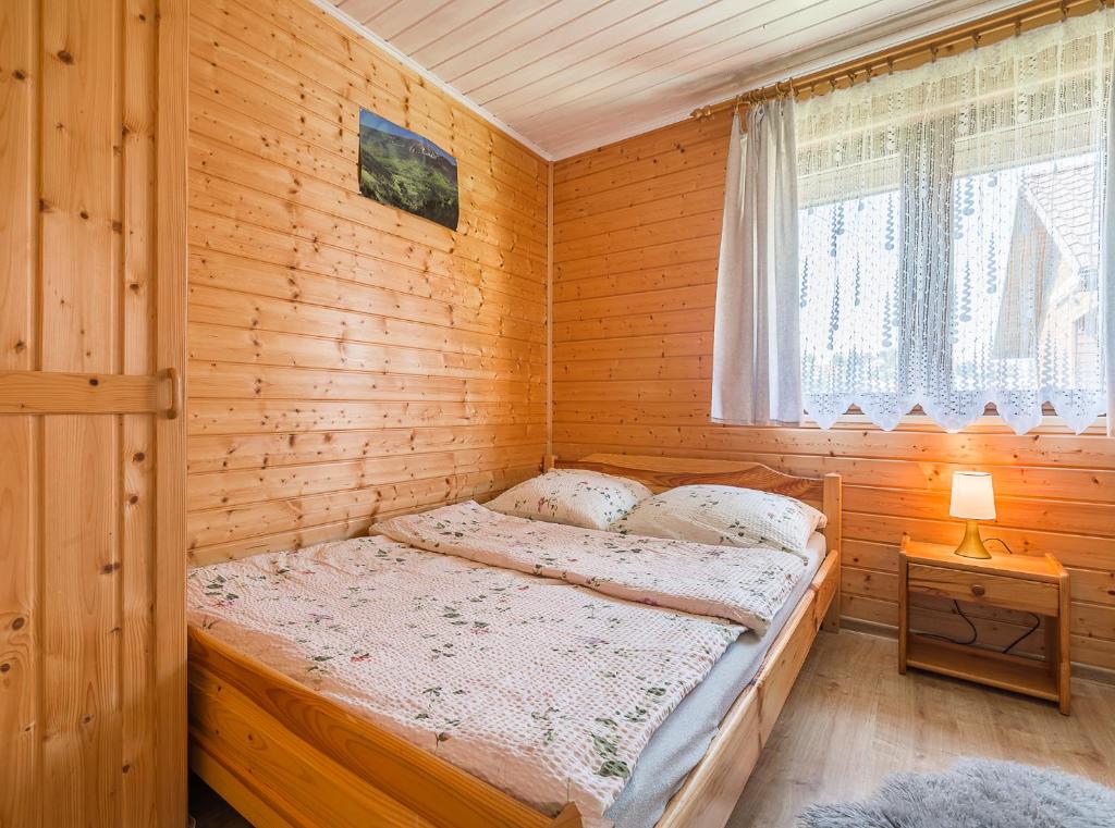 a bedroom with a bed in a wooden cabin at "Widokowe Wzgórze"domki z widokiem na jezioro w Polańczyku z klimatyzacją in Polańczyk