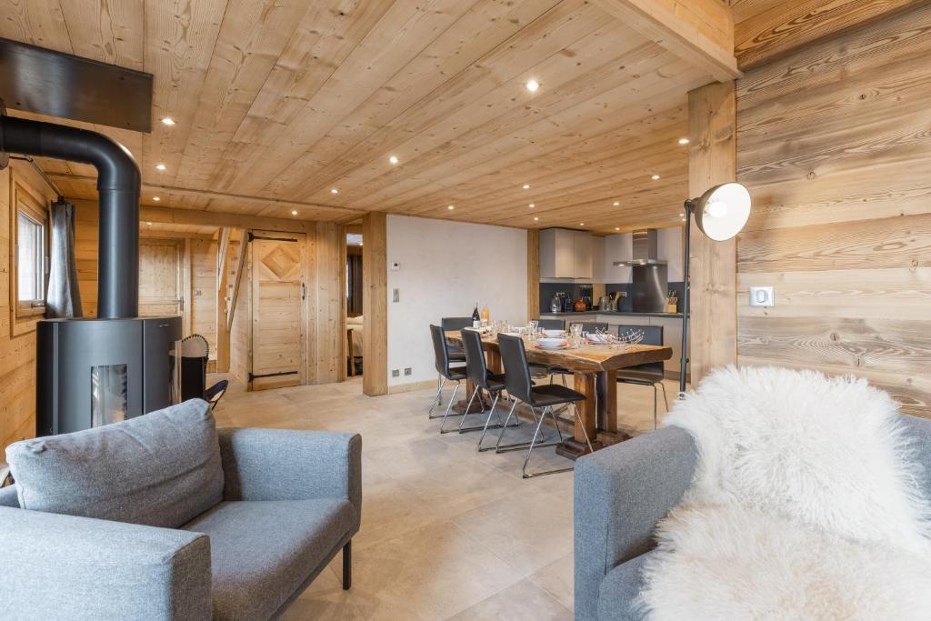 un salon avec une cheminée et une table avec des chaises dans l'établissement Chalet Karavi, à Manigod