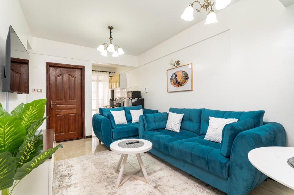 a living room with a blue couch and a table at 1 Bed and exta bedroom at Kilimani Yaya centre-Nairobi in Nairobi