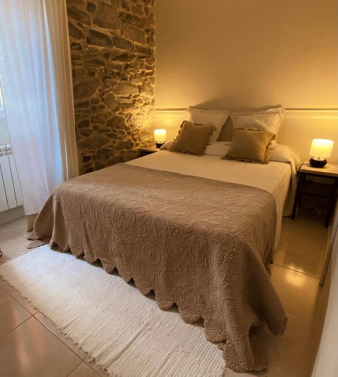 a bedroom with a large bed with a stone wall at Alojamiento Virita in Nigrán