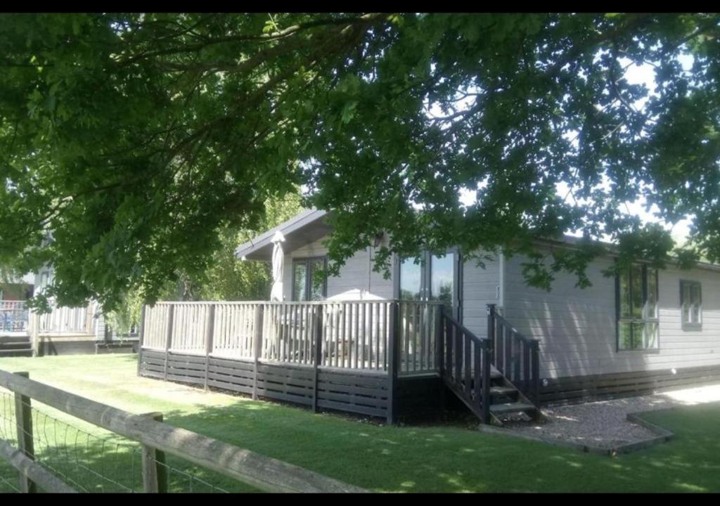 ein weißes Haus mit einer Veranda und einem Zaun in der Unterkunft Rainbow Petty - Romney Marsh, Kent in Brookland