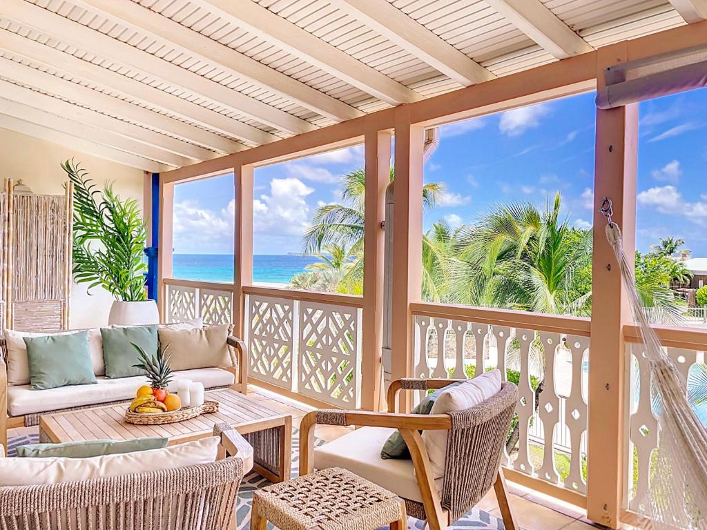 una veranda schermata con vista sull'oceano di Sable Bleu Elegant 2-Bedroom Oceanfront Apartment a Orient Bay