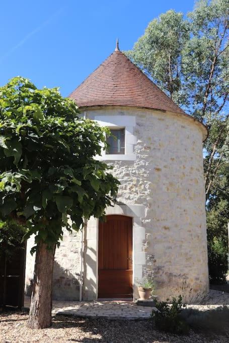 un petit bâtiment avec une porte en bois et un arbre dans l'établissement La tour du Périgord, à Beaupouyet