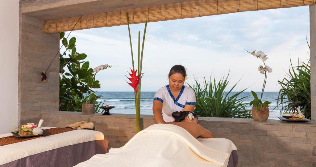 a woman giving a woman a massage in a spa room at Kelapa Retreat & Spa in Pulukan