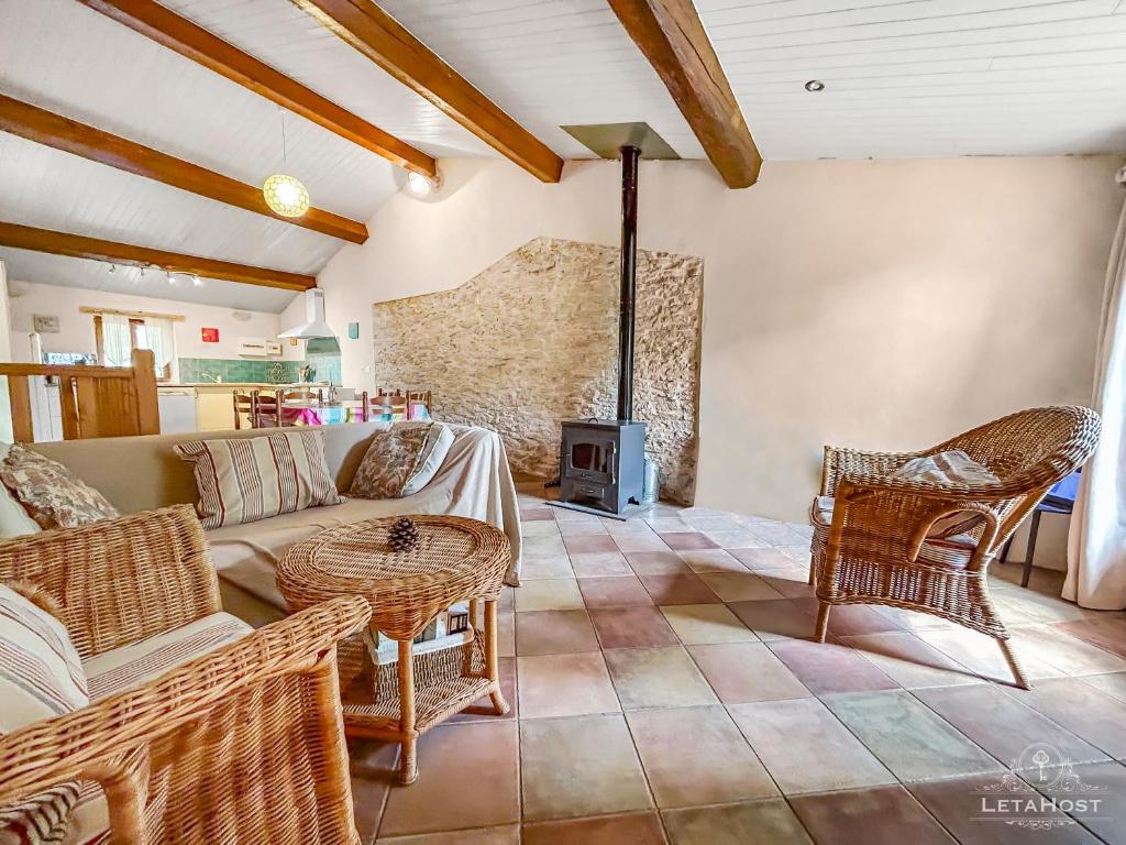 een woonkamer met een bank en stoelen en een open haard bij Charme rustique avec jardin privé "Au Pastel" in Soupex