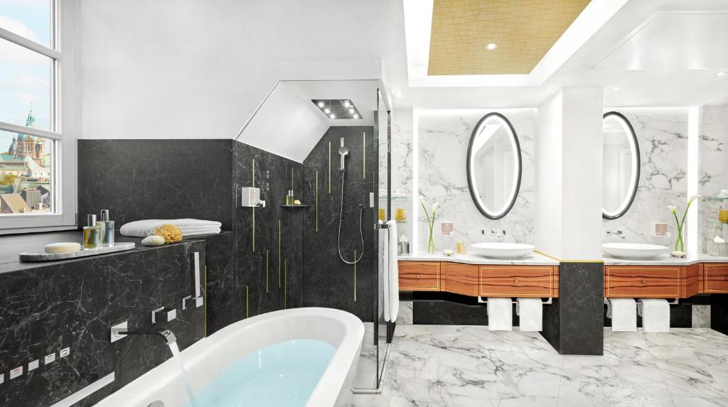 a bathroom with a tub and two sinks and mirrors at Mandarin Oriental, Munich in Munich