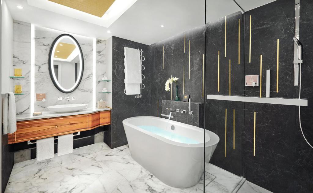 a bathroom with a tub and a sink and a mirror at Mandarin Oriental, Munich in Munich