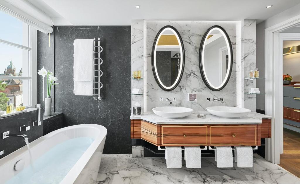 a bathroom with two sinks and two mirrors at Mandarin Oriental, Munich in Munich