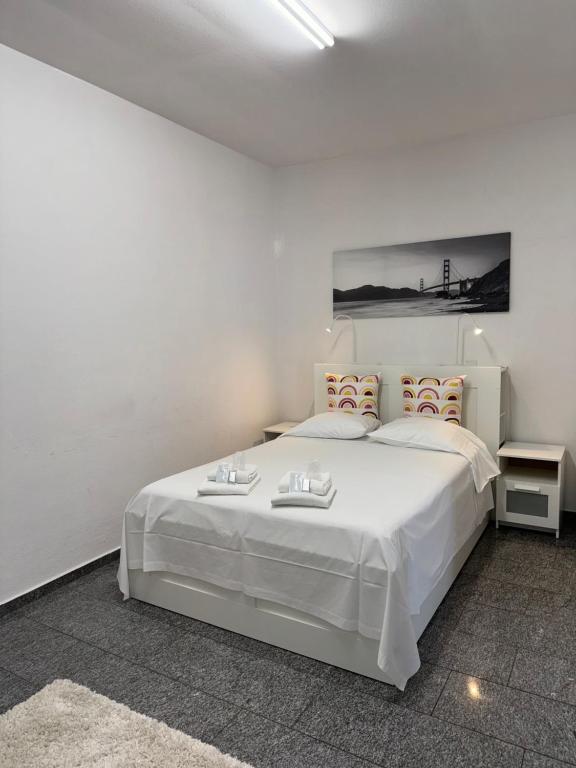 een witte slaapkamer met een groot wit bed en 2 tafels bij B&B Ilien in Bellinzona