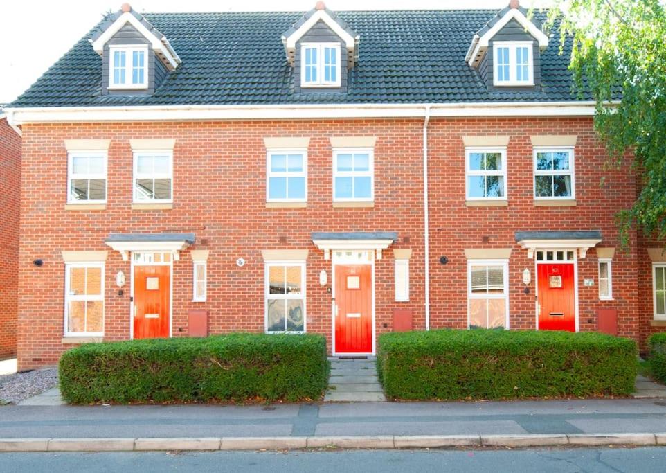 a red brick house with red doors on a street at The Voyager - Newly Furnished Home in Derby