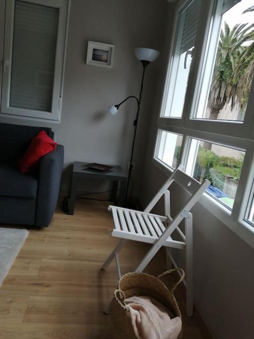 a living room with a chair and two windows at Apartamento Salgueiro ORTIGUEIRA in Santa Marta de Ortigueira