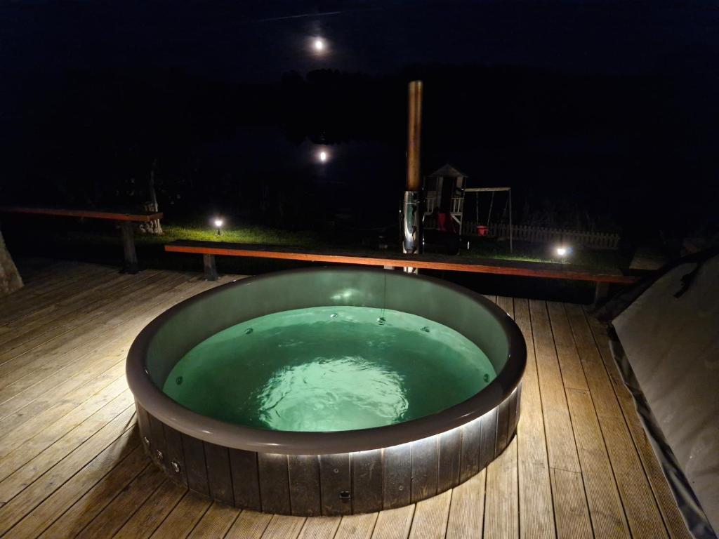 a hot tub on a deck at night at Ezerdzirnas in Celmenieki