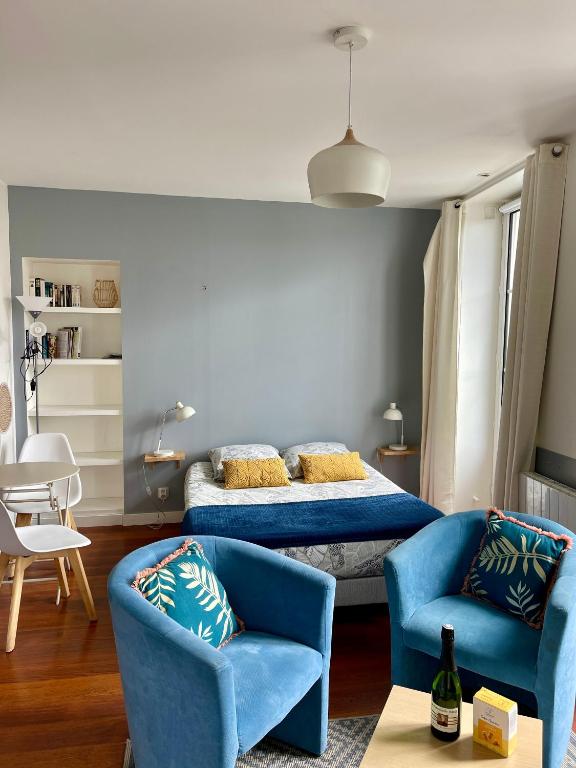 - une chambre avec un lit et deux chaises bleues dans l'établissement Le balcon de la place, à Dinan