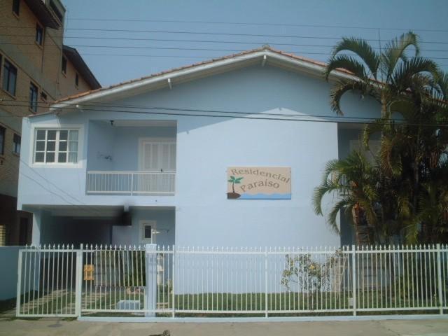 Una casa blanca con un cartel en el costado. en Residencial Paraiso, en Florianópolis